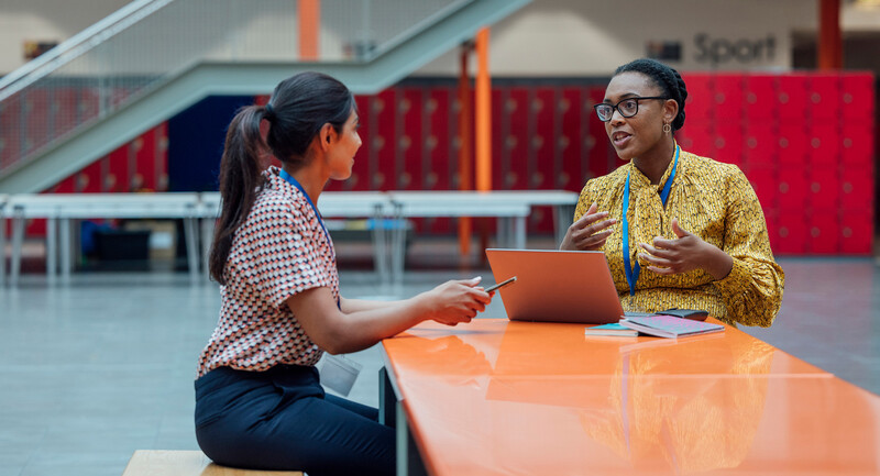 An educator and a coach engaged in discussion at a conference table.